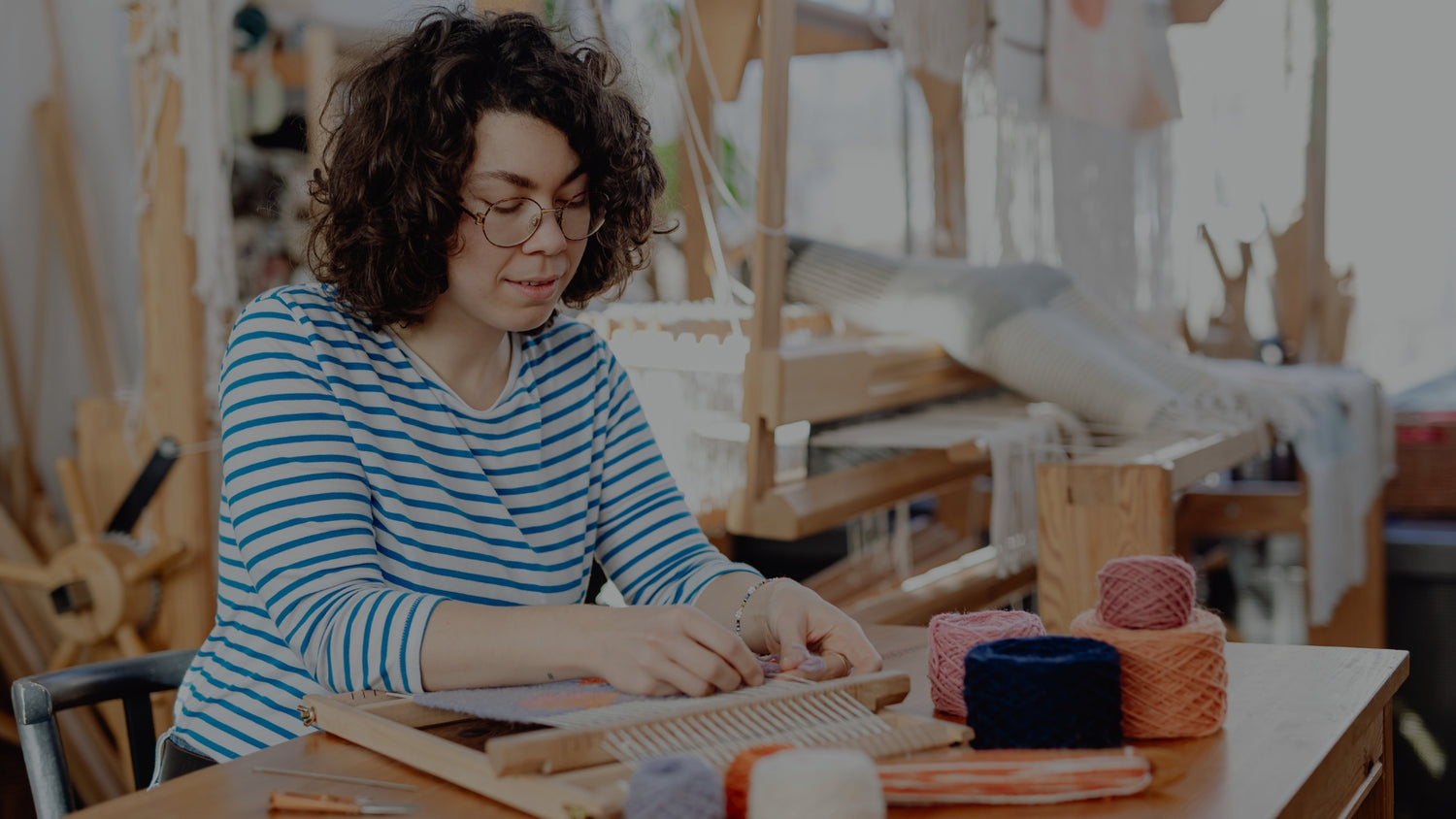 Woman working with yarn and fabric in a weaving studio